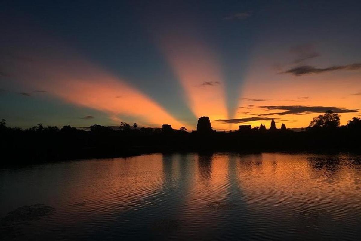 Una puesta de sol con un arcoíris en el cielo sobre un lago.