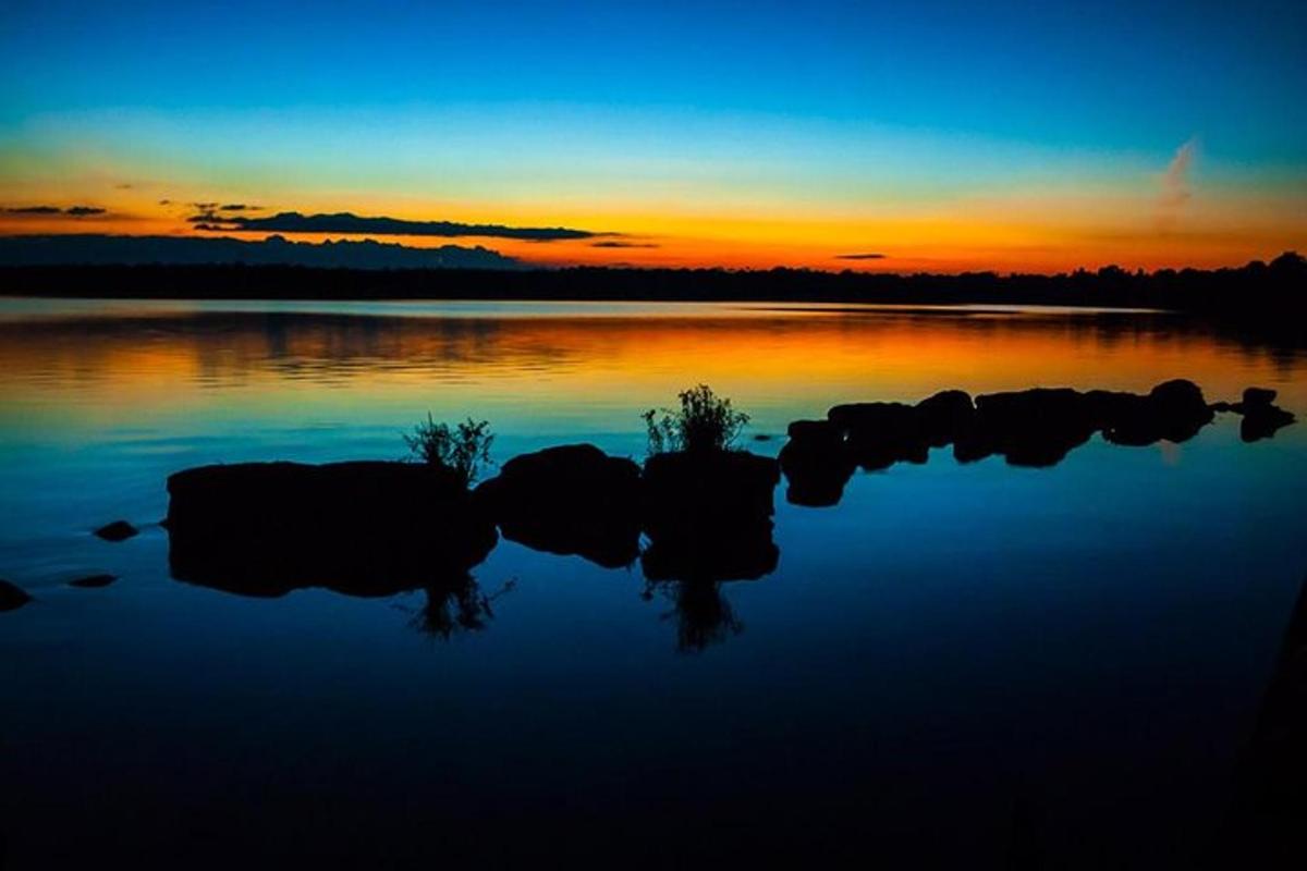 a sunset over a lake with rocks in the water