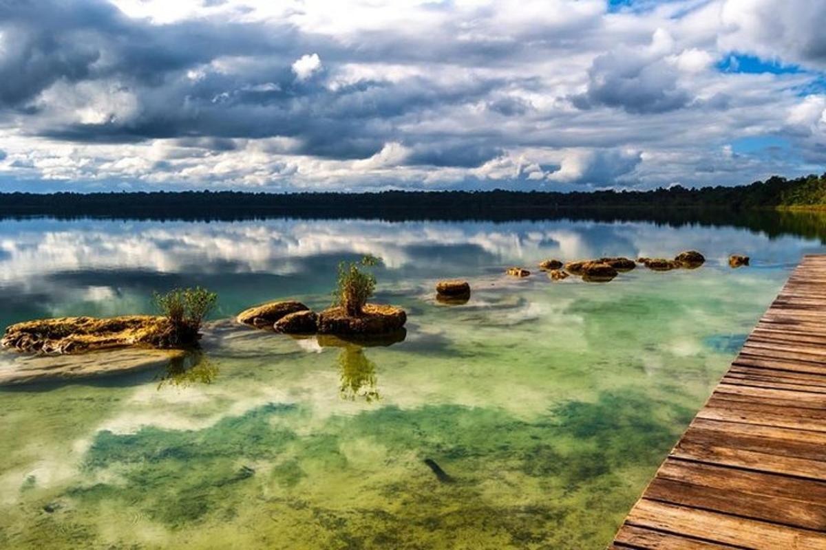 a lake with rocks in the water and a wooden pier