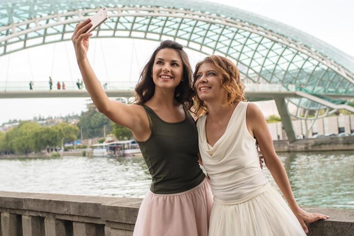 dvě ženy stojící vedle řeky a držící fotoaparát