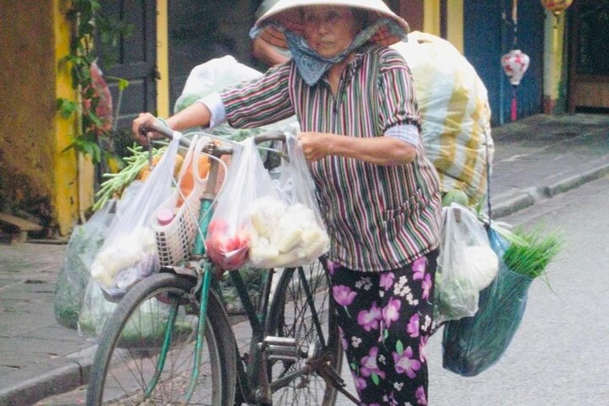 Una mujer que camina en bicicleta con bolsas de comestibles