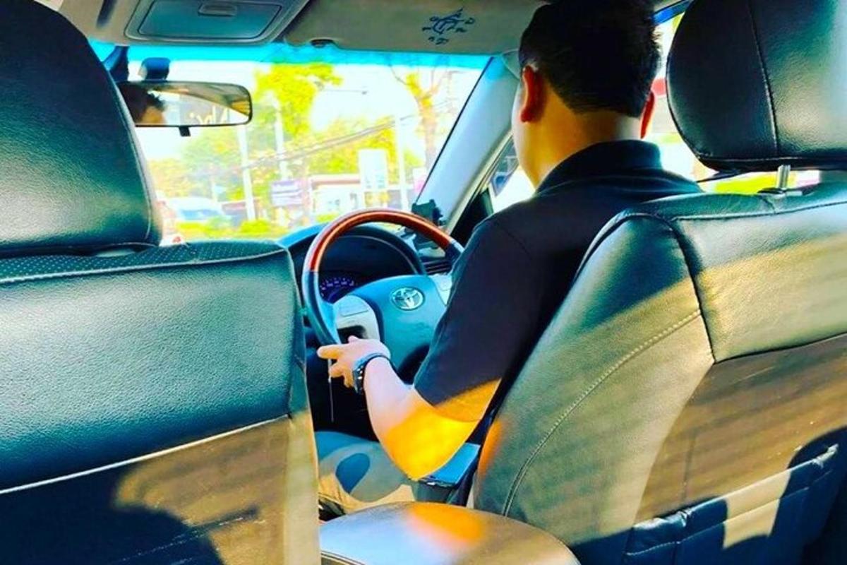un home conduint un cotxe per un carrer