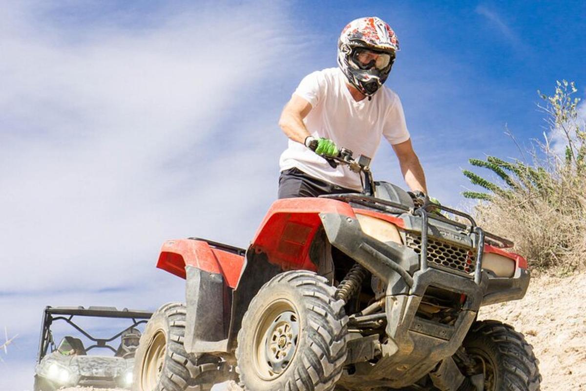 un uomo in sella a un quad sulla spiaggia