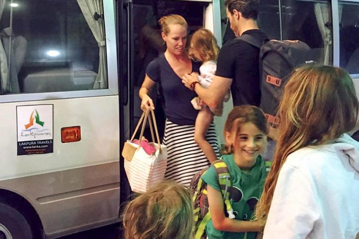 žena držící dítě stojící vedle autobusu