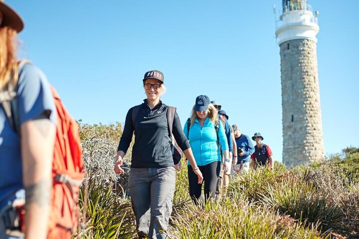 a group of people walking on a trail near a lighthouse