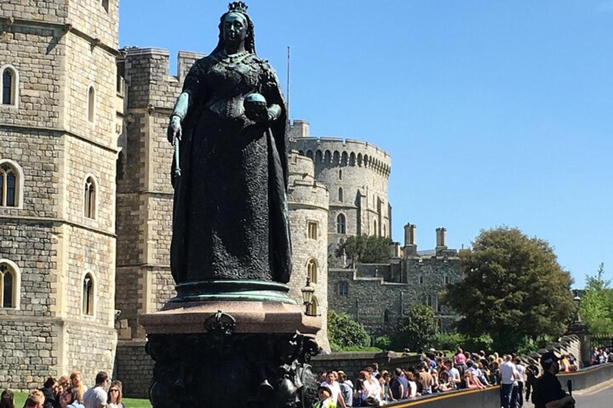 eine Menschenmenge, die um eine Statue vor einem Schloss steht