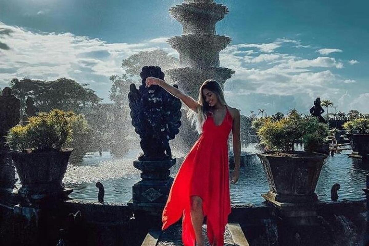 一位身穿红裙的女子站在喷泉前