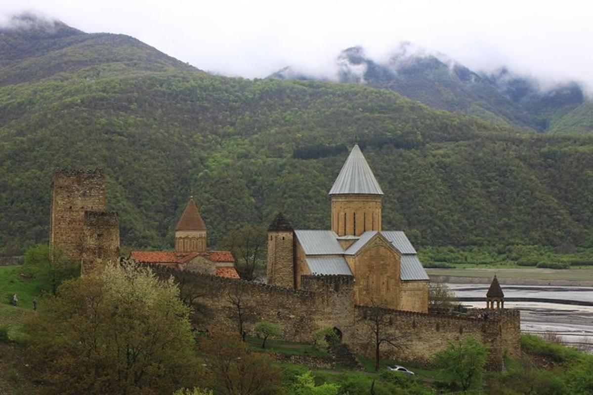 um antigo castelo em uma colina com montanhas ao fundo