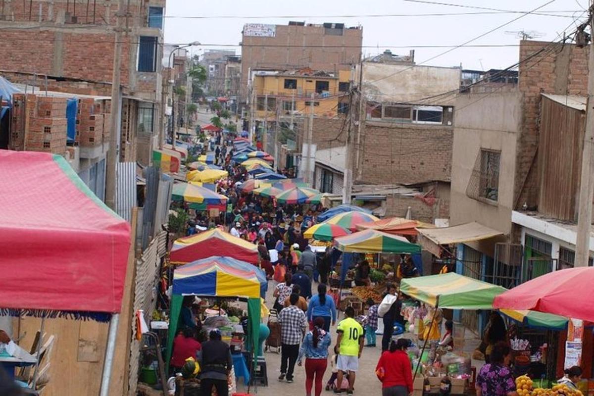uma multidão de pessoas caminhando por um mercado com guarda-chuvas