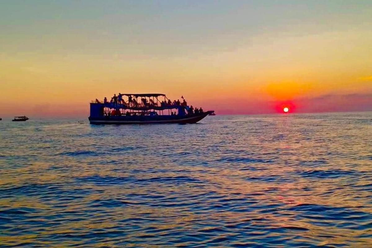 Un grupo de personas en un barco en el océano al atardecer