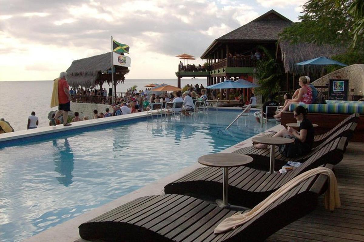 una piscina in un resort con persone sedute su panchine