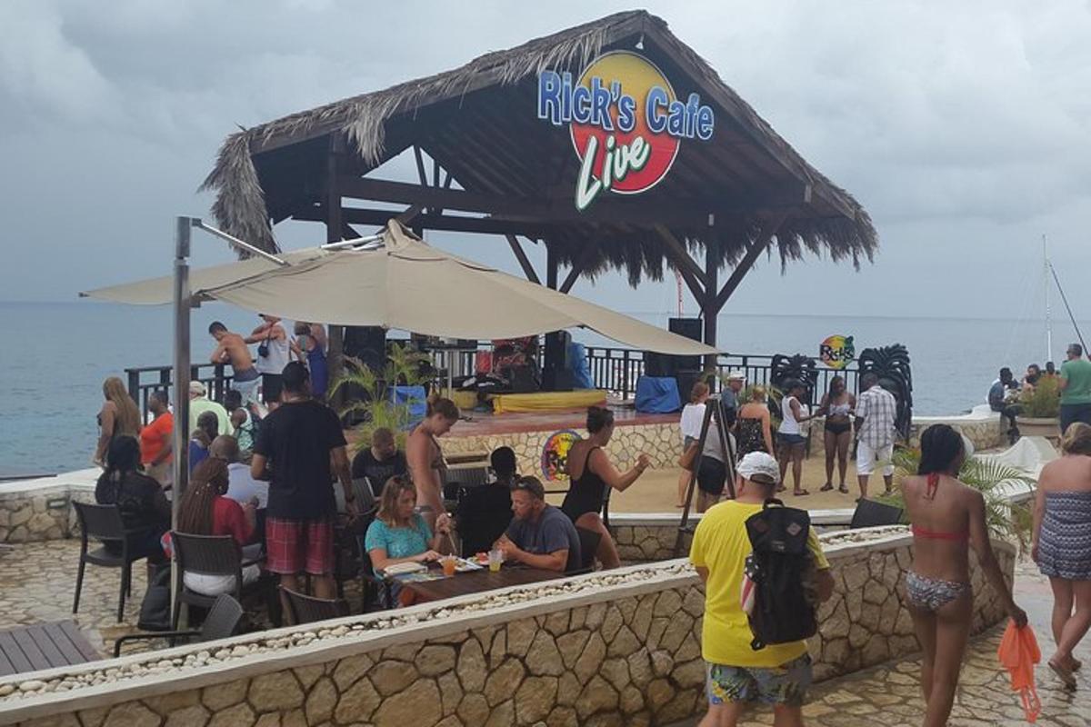 un gruppo di persone in piedi attorno a un bar sulla spiaggia
