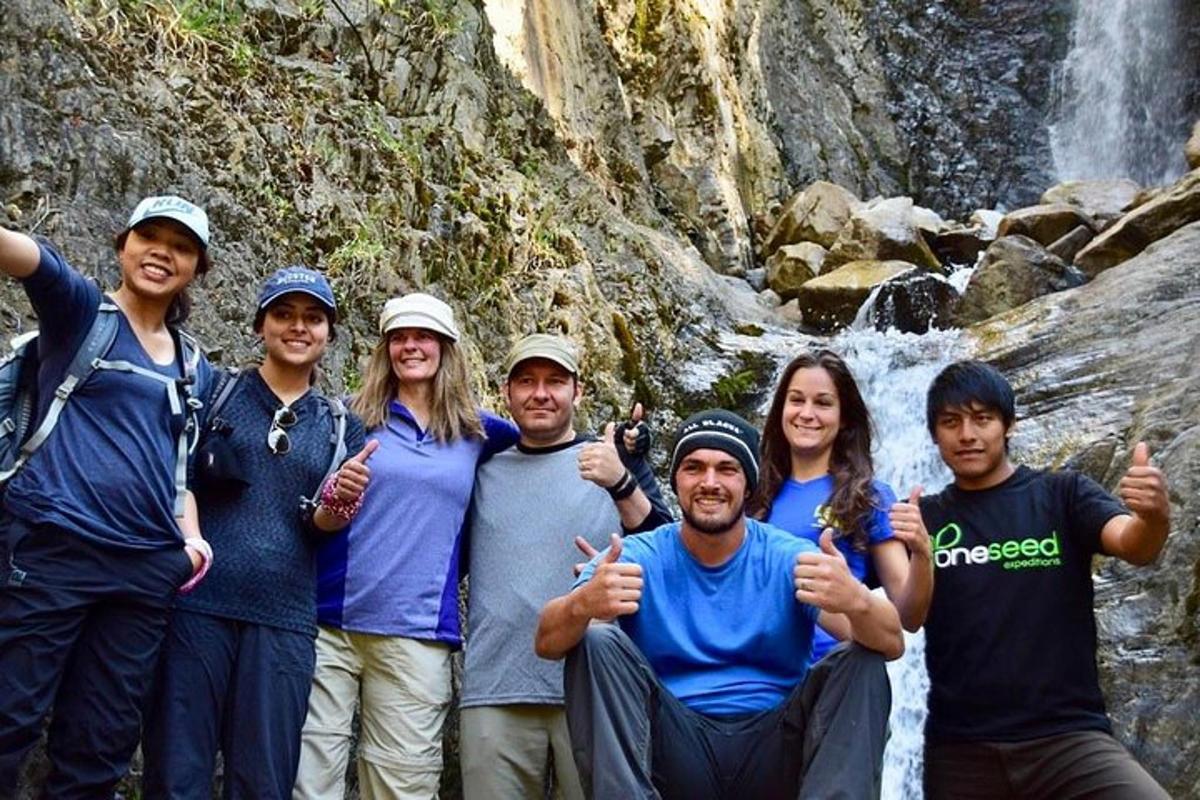 um grupo de pessoas fazendo sinal de positivo em frente a uma cachoeira