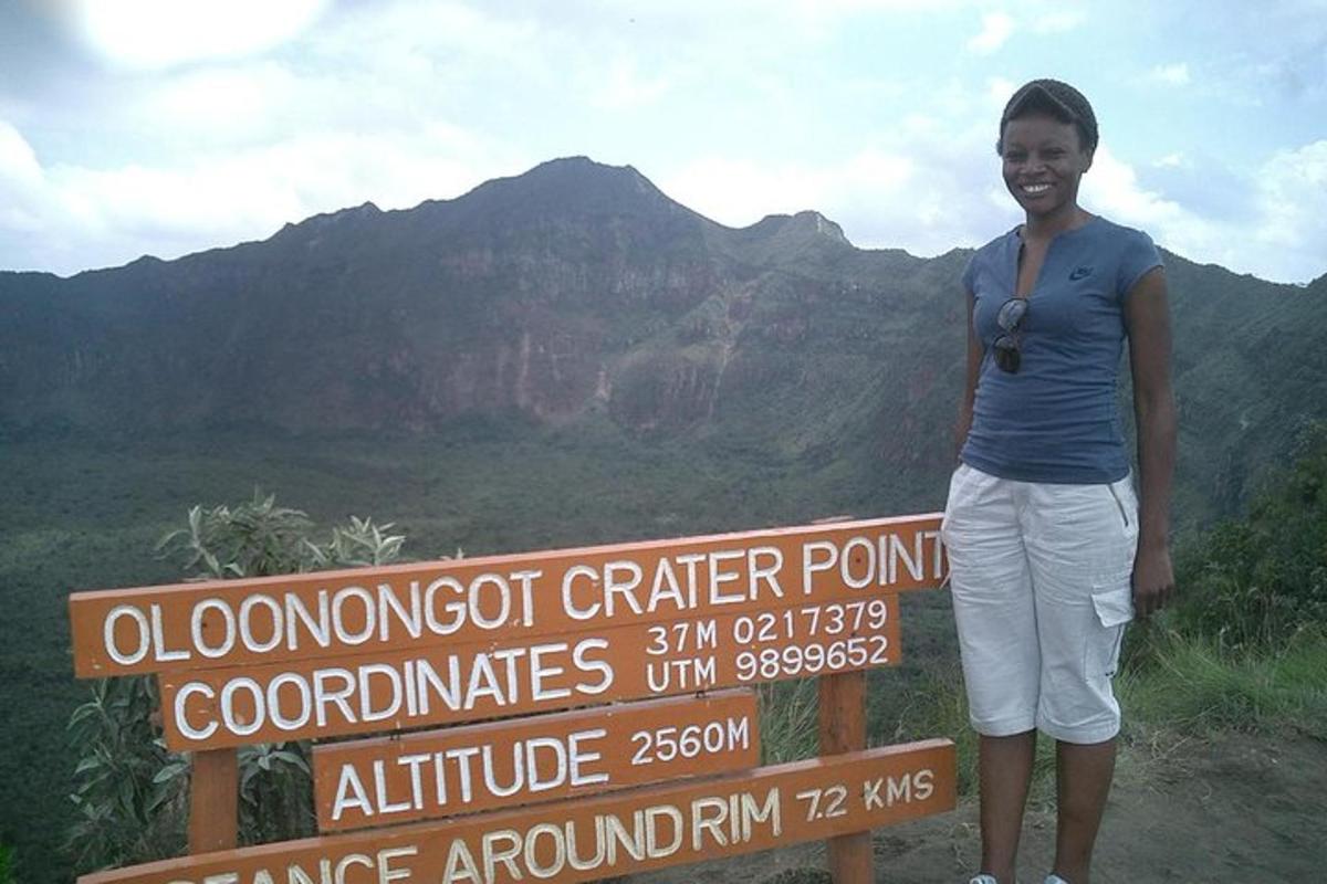 Una mujer parada junto a un cartel en una montaña