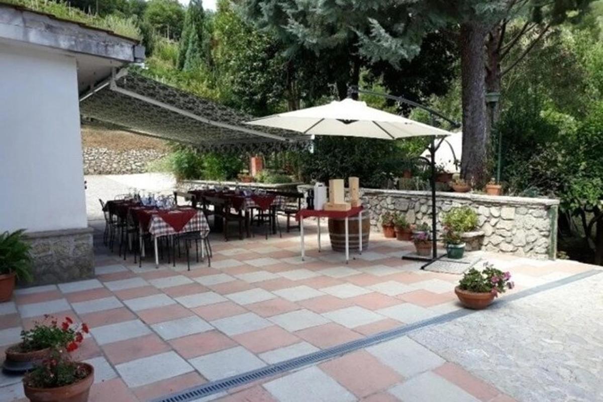 μια βεράντα με τραπέζια και καρέκλες και μια ομπρέλα