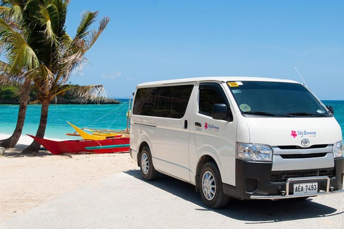 a white van parked on the beach next to a boat