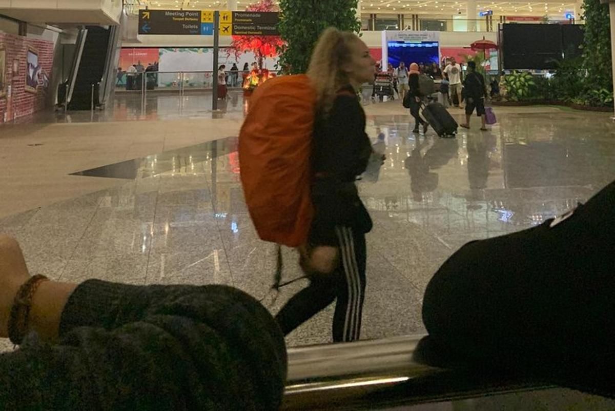 žena procházející letištěm se svými zavazadly