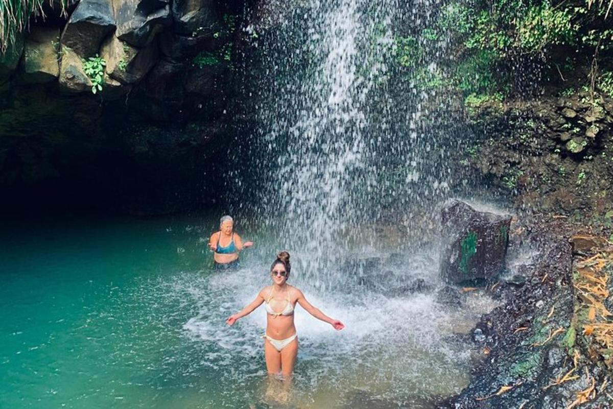 two women in the water in front of a waterfall