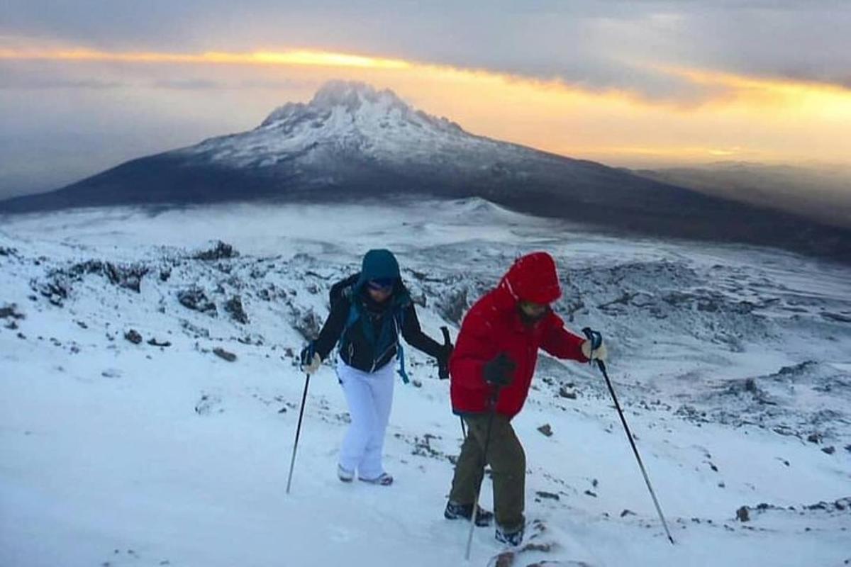 dos personas con esquís en la cima de una montaña