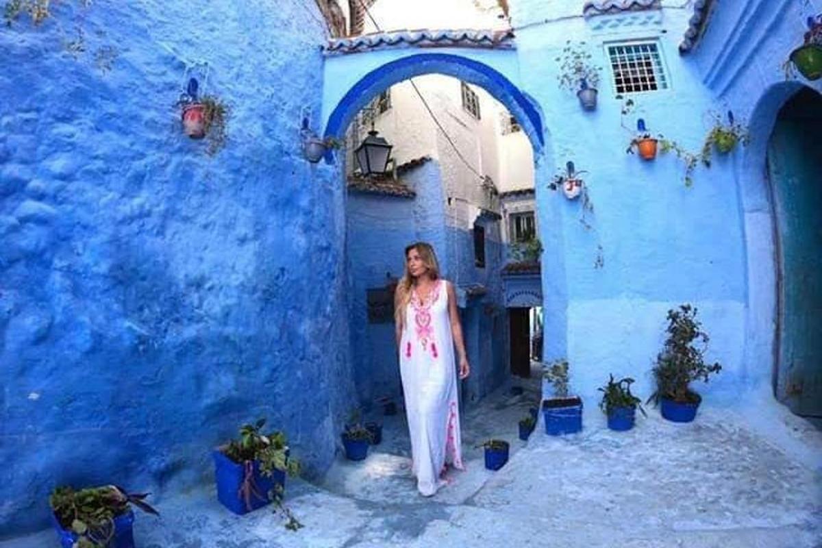 una donna in piedi in un vicolo di fronte a un edificio blu