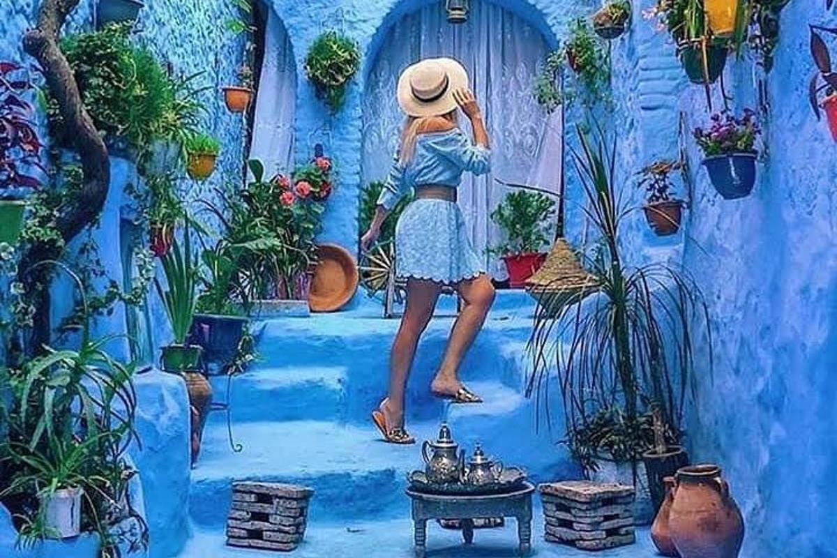 a painting of a woman wearing a hat standing on a blue wall