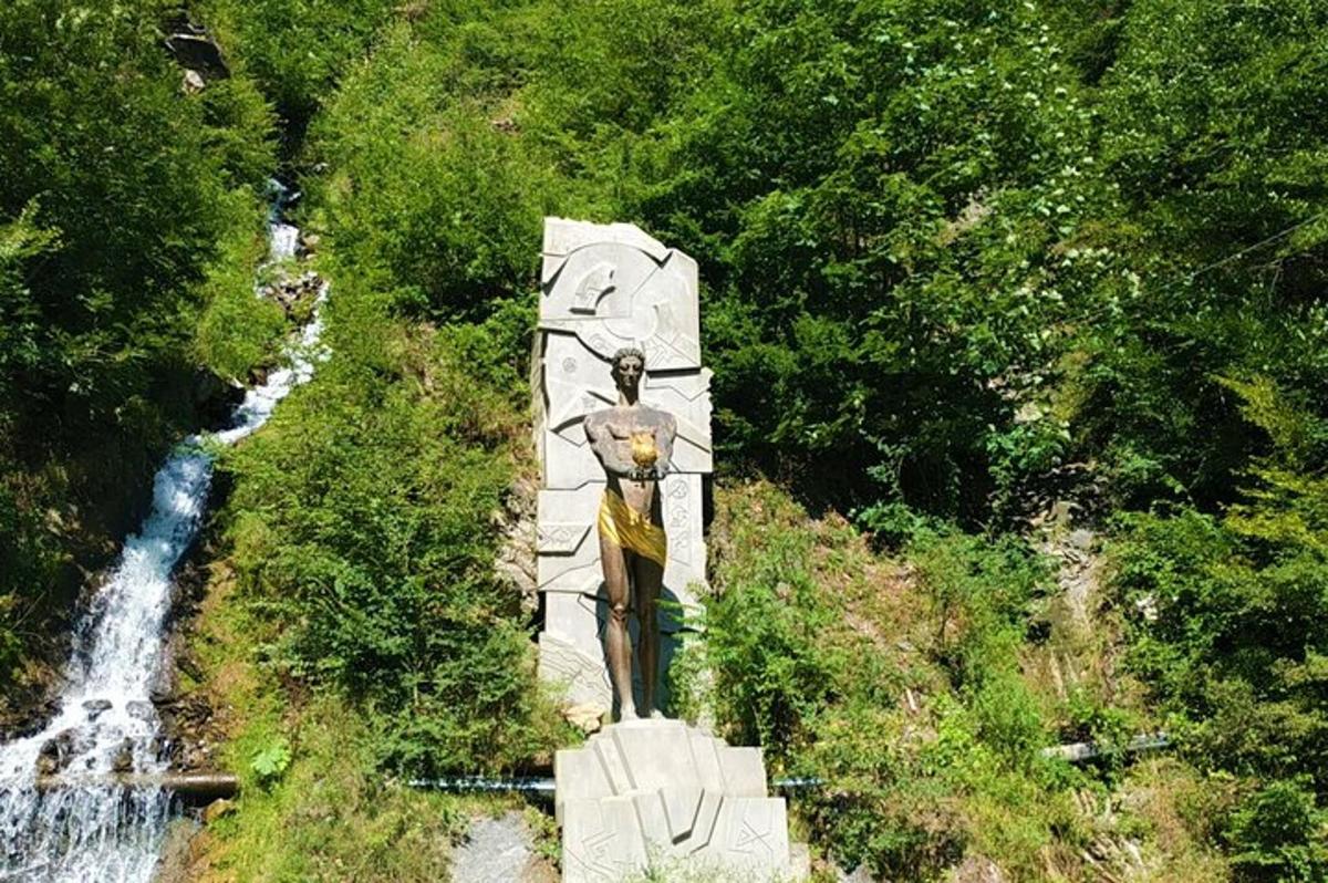 una estatua en medio de un bosque con una cascada