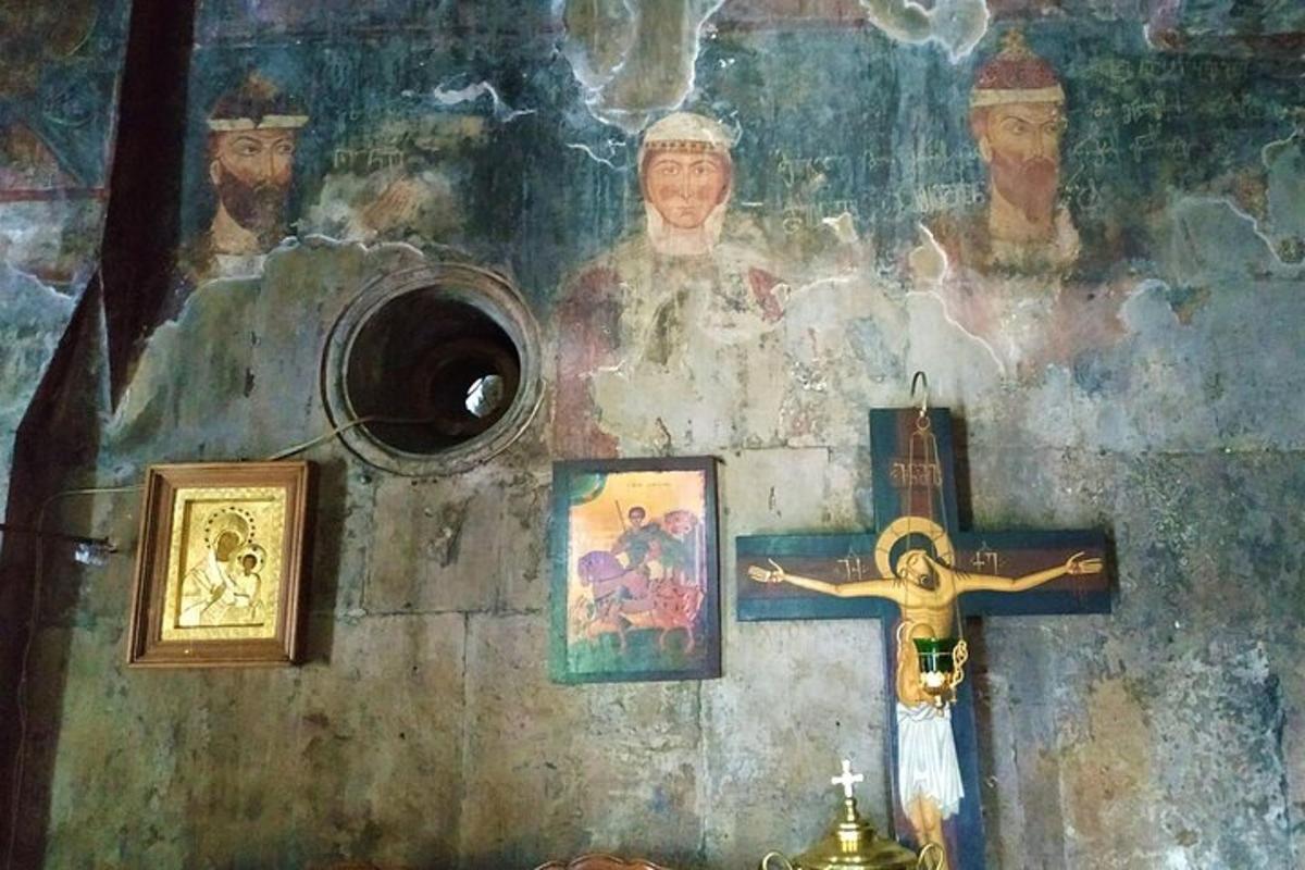 Una cruz en una pared con imágenes y una pintura.