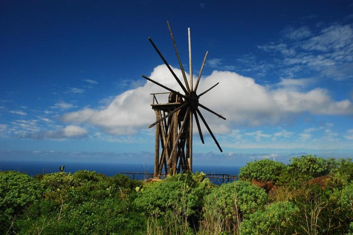 a windmill on top of a hill with the ocean
