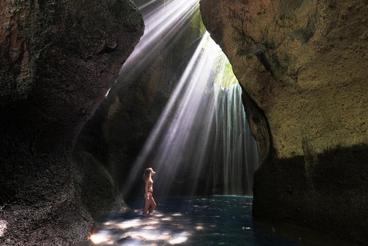 a woman standing in a pool of water in front of a waterfall