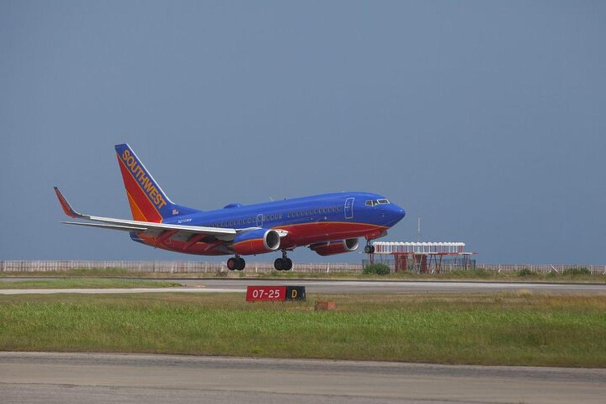 um avião azul e vermelho decolando da pista de um aeroporto