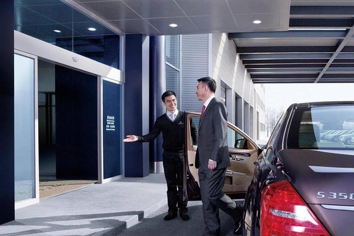 two men are standing outside of a car dealership