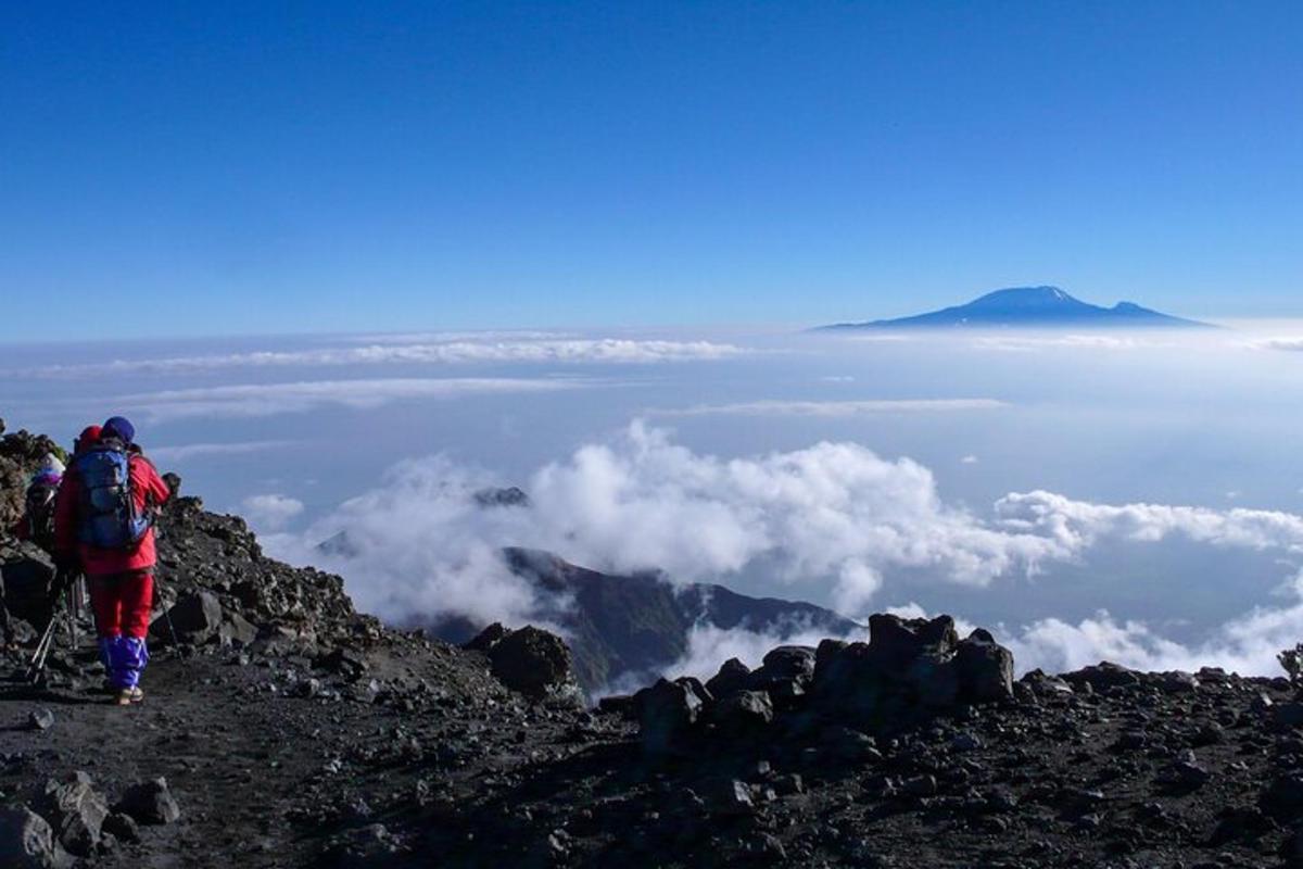 una persona in piedi sulla cima di una montagna con le nuvole