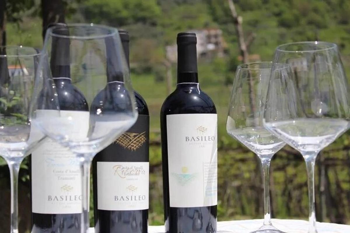 tri steklenice vina na mizi s kozarci