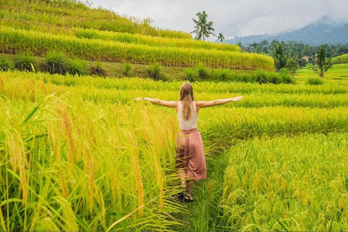 Una mujer caminando por un campo con los brazos extendidos.