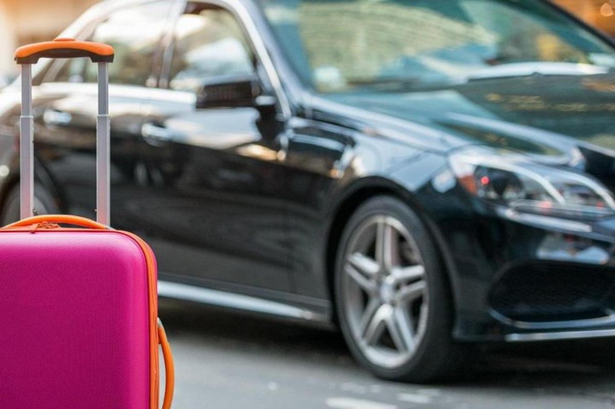 černé auto zaparkované vedle růžového kufru