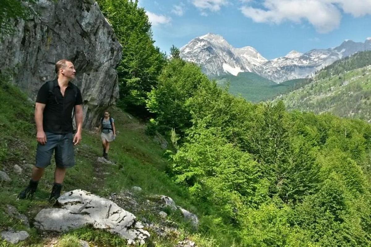 Δύο άνθρωποι περπατούν σε ένα ορεινό μονοπάτι με βουνά στο φόντο