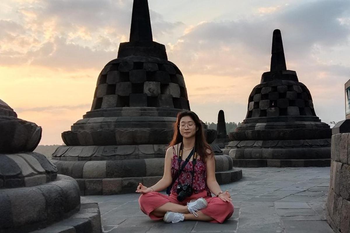 a woman sitting in meditation in front of a temple