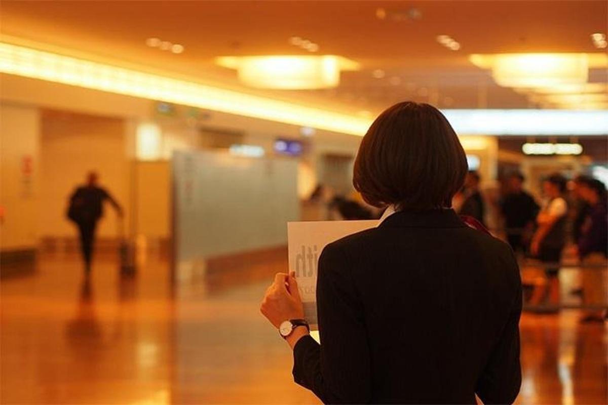 a woman standing in a hallway holding a sign