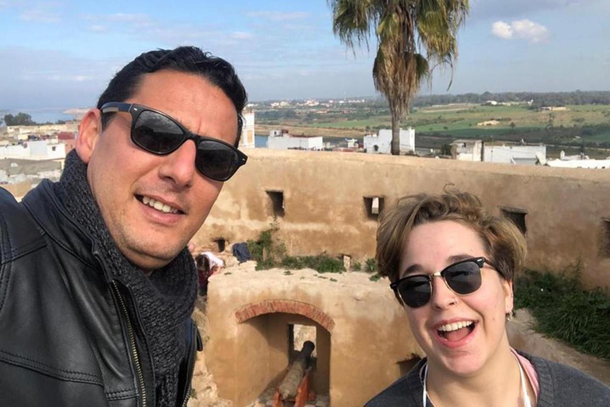 Un hombre y una mujer con gafas de sol de pie frente a un edificio.