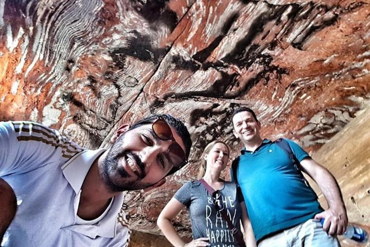 three people standing in front of a rock wall