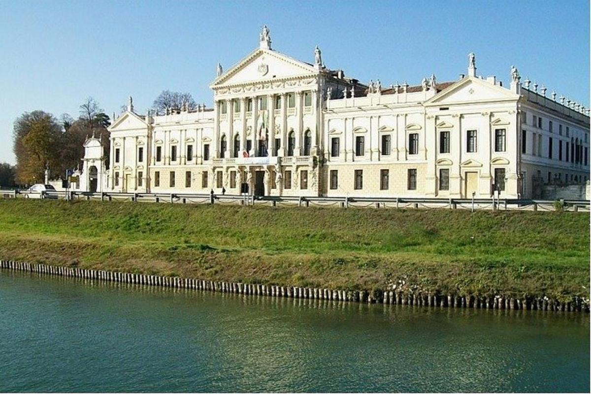 velika bela stavba na hribu ob vodni površini