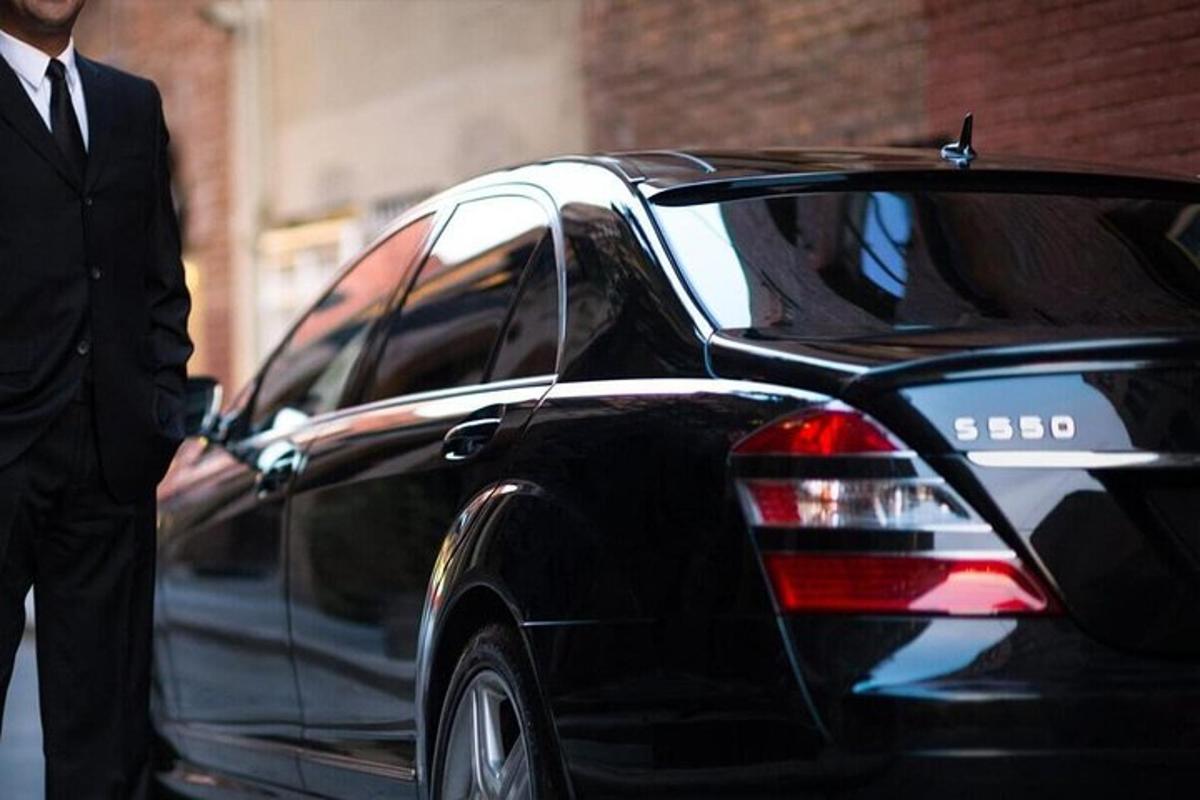 um homem de terno parado ao lado de um carro preto