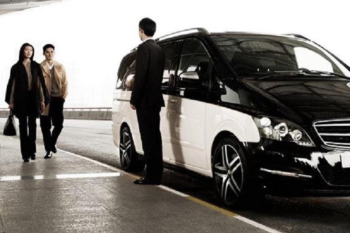 a man standing next to a car parked in a parking lot