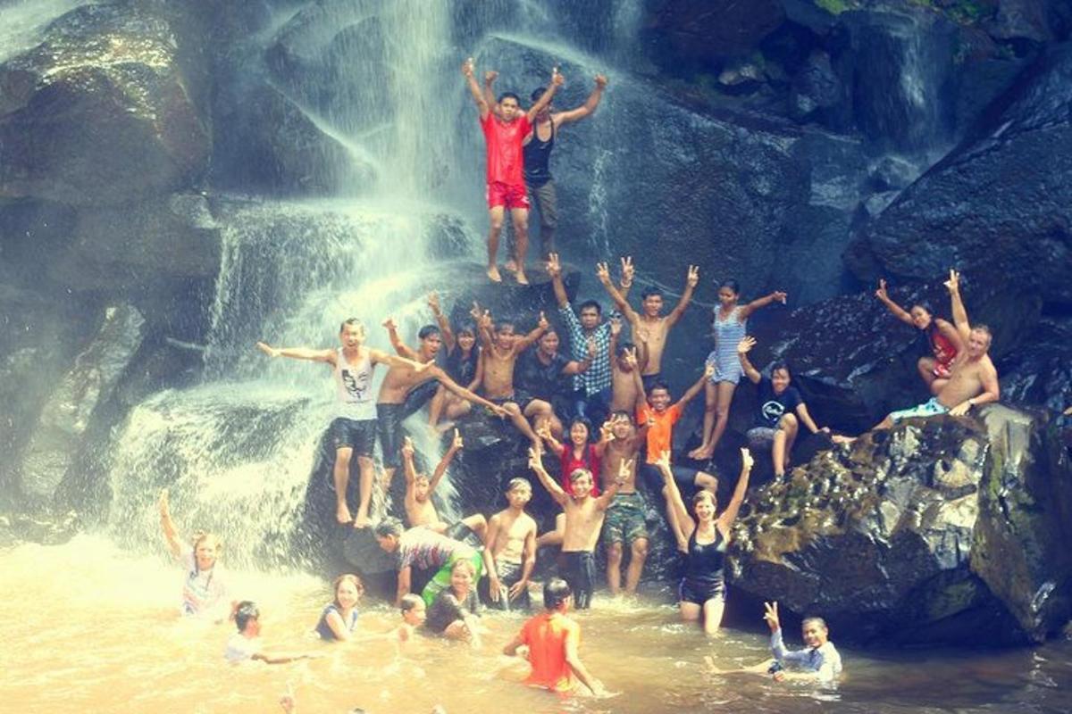 hópur fólks í vatninu fyrir framan foss