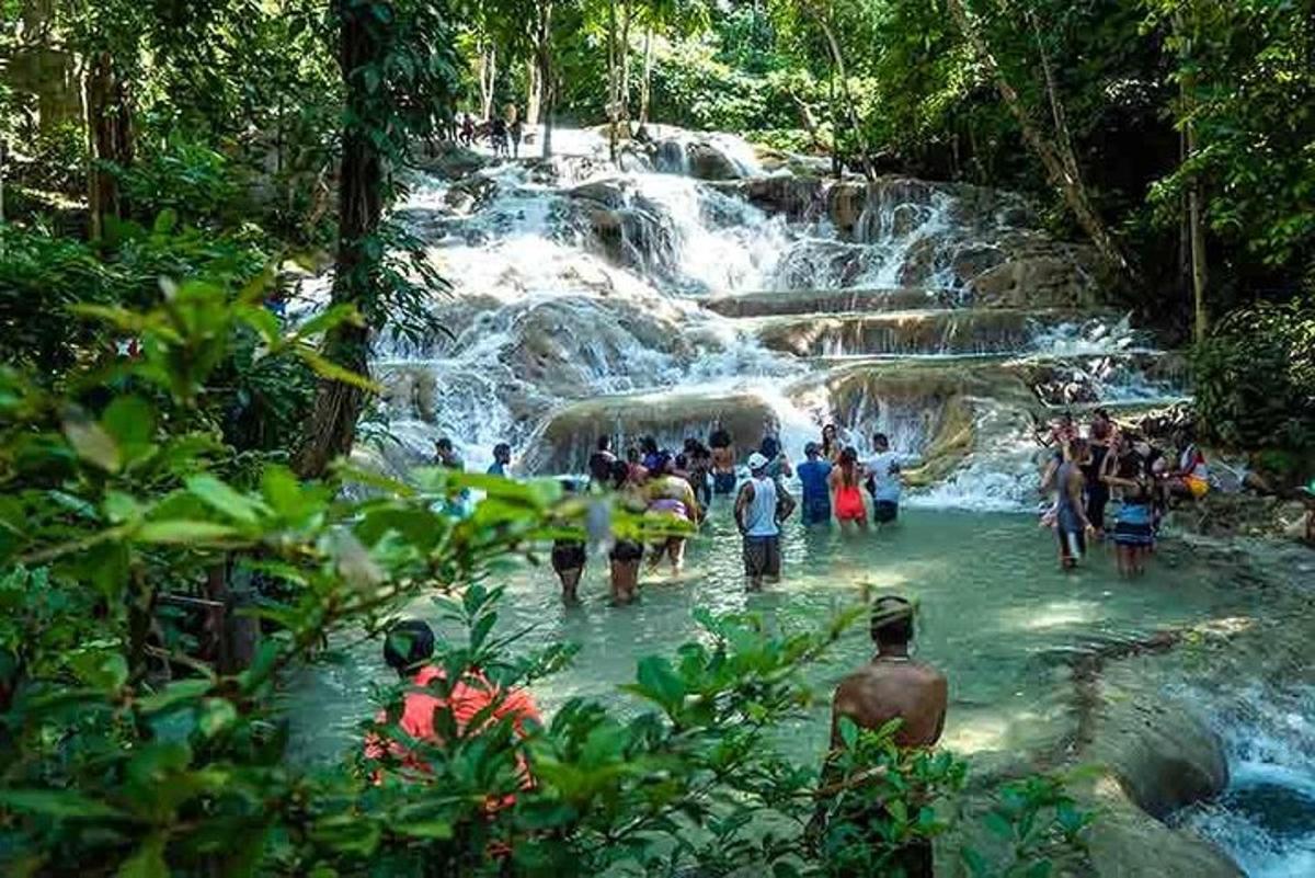 một nhóm người đứng dưới nước gần thác nước