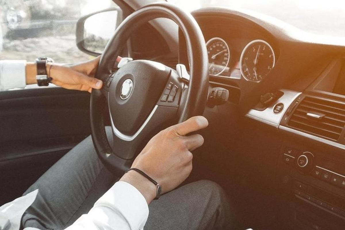 uma pessoa dirigindo um carro enquanto segura o volante