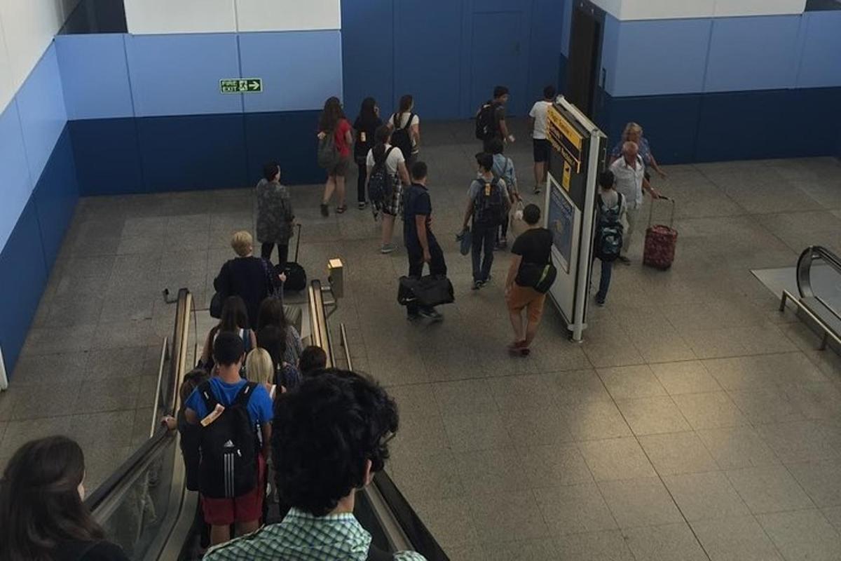 skupina lidí scházejících po eskalátoru na letišti