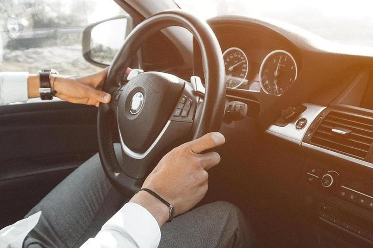 osoba řídící auto a zároveň držící volant