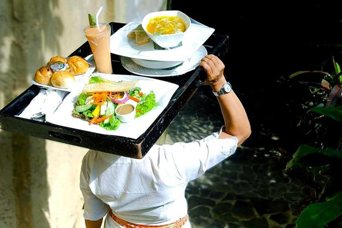 isang babae na may dalang tray ng pagkain sa kanyang ulo