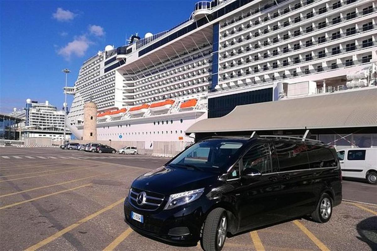 a black car parked in a parking lot in front of a cruise ship